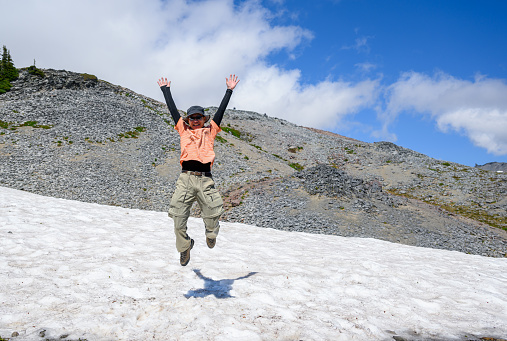 Man jumping on a patch of snow at Skyline Trail. Mt Rainier National Park. Washington State.