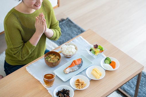 Young Japanese woman eating breakfast in the living room