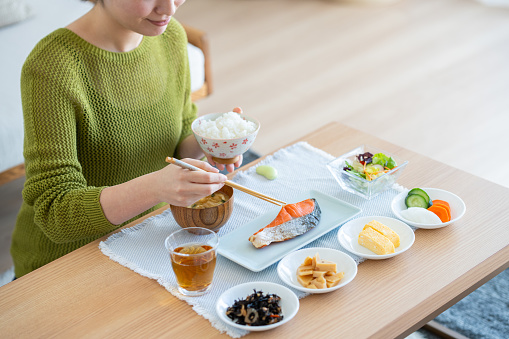 Young Japanese woman eating breakfast in the living room