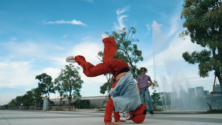 Asian skilled hipster doing freeze pose at camera near fountain. Sprightly.