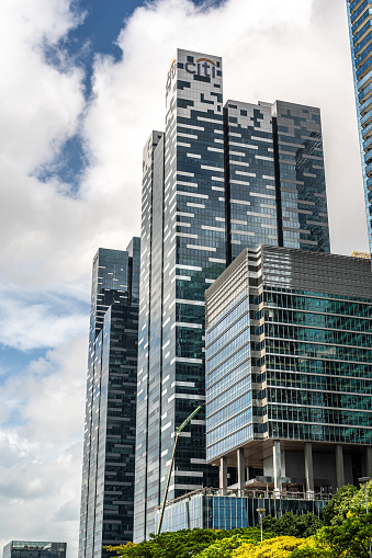 Singapore, 26 January 2024: skyscrapers, symbols global business, rise against blue sky and clouds. towering structures epitomize corporate dominance. vertical photo