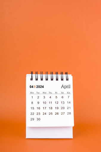 Vertical of April 2024 table calendar on orange color background.
