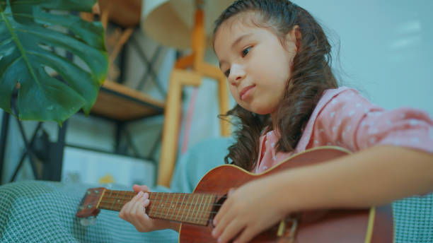 istock Little Chinese Girl Singing and Playing Ukulele. 1978989515