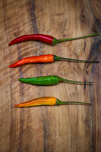 4 multicolored chilies on a wooden cutting board