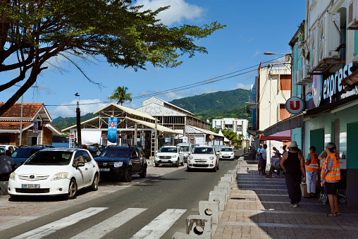 Martinique, Saint Pierre - November 26, 2023: City life of the busy commercial of Saint-Pierre with the public market in background. The town was destroyed in 1902 by the catastrophic volcanic eruption of Mt Pelé.