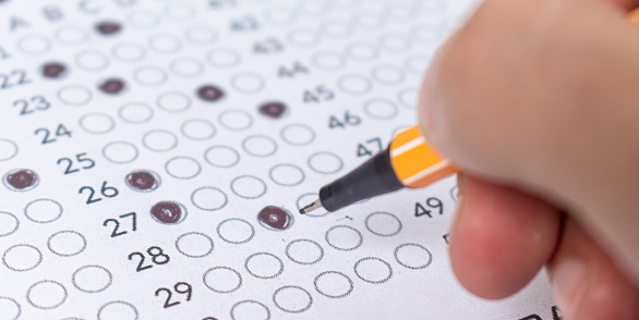 Rellenar a mano una hoja de respuestas de examen con bolígrafo, concepto para exámenes públicos y de ingreso. photo