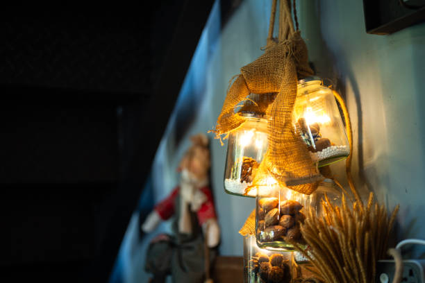 Glowing lighting bulb in glass containment is place at the corner in dark environment for interior decoration. Photo contain some noise due to low light condition.