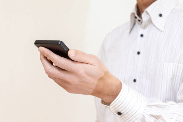 istock A man in a white shirt holding a smartphone in one hand 1979120164
