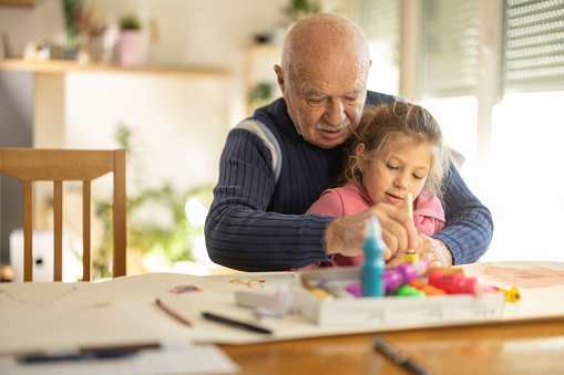 Grandfather and granddaughter enjoying making craft products together at home