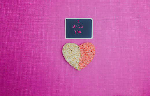 I Miss You chalk message with pink and white rice treat heart on pink background.  Romantic Message for Valentines day, Anniversary, Date Night, Long Distance relationship, married, dating.