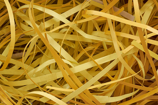 abstract of used discarded packaging straps, aka strapping, banding or bundling, yellow polyester tapes used in packaging and shipping, environmental concern and recycling concept, background texture