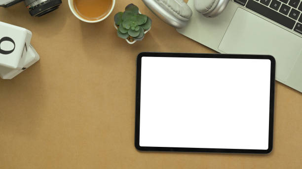 istock Digital tablet with white blank screen, laptop, notepad and headphone on brown background 1979224999