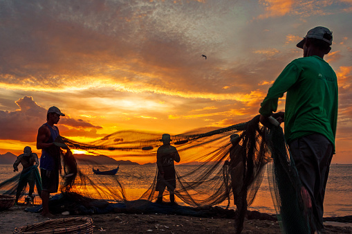 Banda Aceh - Indonesia. February 03, 2016.\n\nA group of fishermen is pulling a land seine on the coast of Gampong Jawa, Banda Aceh city. Land trawling is a tradition of the coastal communities of Aceh that we often encounter today.