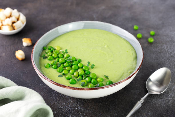 istock Green pea cream soup with croutons on a brown table. 1979244027