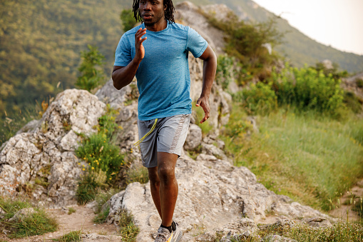 Young African man jogging on rocky mountain
