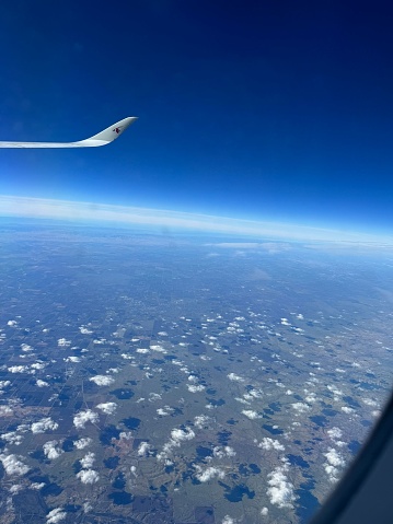 Outside view of clouds and blue horizon small part of plane wings