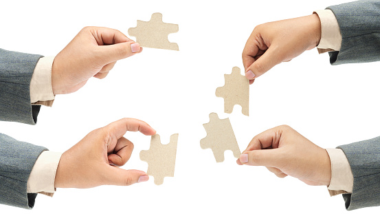 Collection of business hand holding a single piece of puzzle isolated over white background. Teamwork and partnership concept