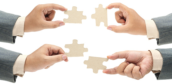 Collection of business hand holding a single piece of puzzle isolated over white background. Teamwork and partnership concept