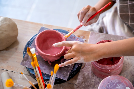 Closeup view of kids making a craft of a porcelain mug from wet clay. Pottery craft clay concept