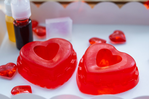 Handmade homemade soap in the shape of hearts for a Valentine's Day gift to your beloved. Perfumes and dyes, soap base on the table