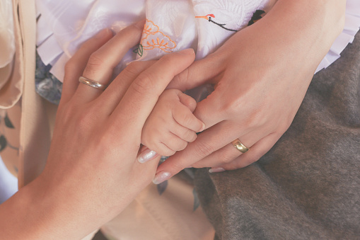 Close up human hands with newborn baby and parents