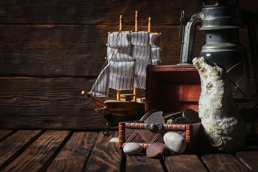 Pirate concept background front view. Sea ship, treasure chest with a coins on the wooden desk table background with copy space.