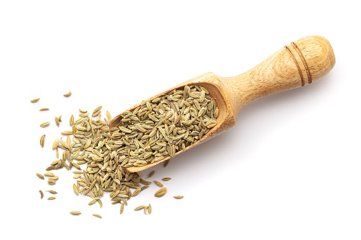 Top view of Organic Fennel Seeds (Foeniculum vulgare) Badi saunf in a wooden scoop. Isolated on a white background.