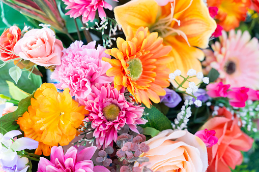 The flowers in the bouquet are a mix of different colors and shapes. There are bright yellow daisies, deep red roses, delicate pink tulips, and pale purple lilacs. The flowers are all in full bloom.