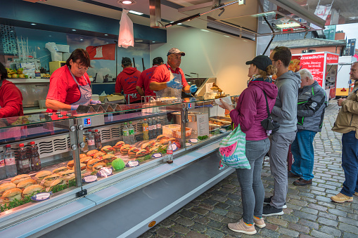 Hamburg, Germany - July 17, 2022: tourists buying fish burger at shop in famous Hamburg fish market (Fischmarkt)