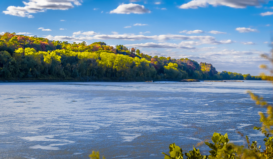 View of Missouri River on nice fall day; river bluffs covered with colorful trees