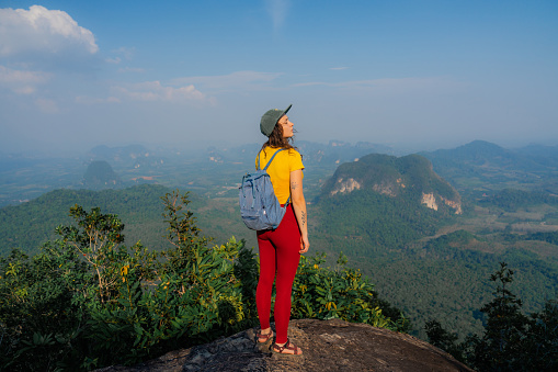 Carefree woman  in cap enjoys scenic view of Krabi province from viewpoint