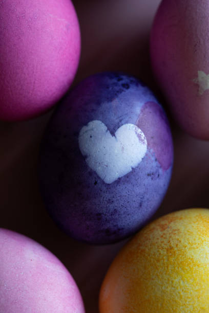 purple egg with heart dyed blueberries for easter on blue background.