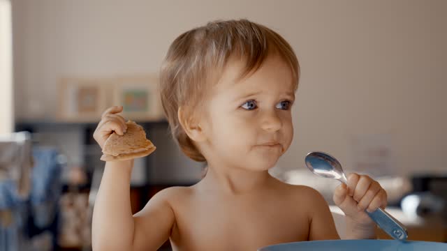 Young Boy Holding a Spoon and a Cookie