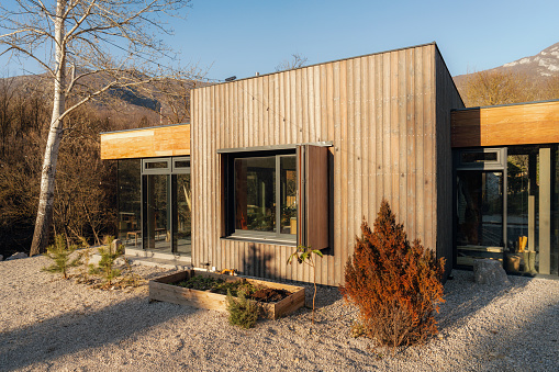 Photo of an exterior that combines natural materials: wood and a glass, on a vacation home on a riverbank, away from the city