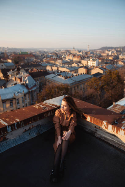 istock Young woman in dress posing on rooftop at sunset 1979415565