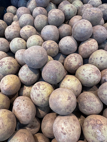 Stock photo showing a plastic crate full of Indian chiku fruit being sold in a supermarket. Also commonly known as sweet exotic sapodilla fruit, chikus are the alternative names of sapotas.