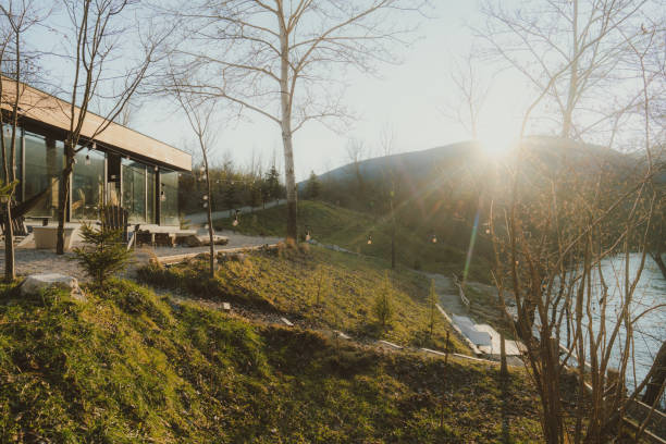 Photo of a wooden cabin house on riverbank, and its sliding glass door that lets the nature get in