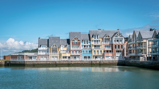 Several houses line the shoreline of a picturesque harbor in the town by the water