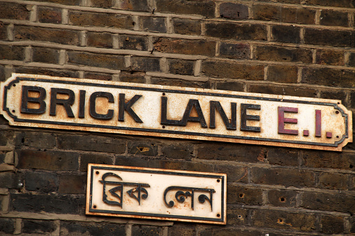 A vintage sign hanging on a brick building on a street in Shoreditch, London