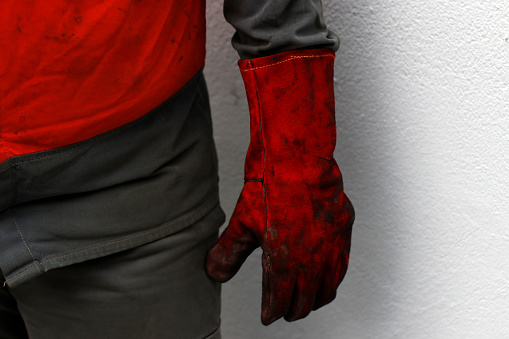 A male worker wearing red protective gloves on a construction site
