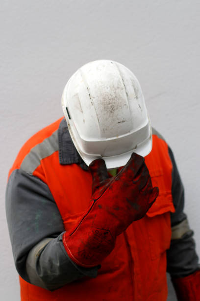 istock Tired worker after a shift in an orange jacket and helmet gently 1979444891
