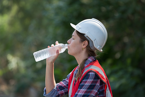 Female engineer drinking water at construction site railway maintenance
