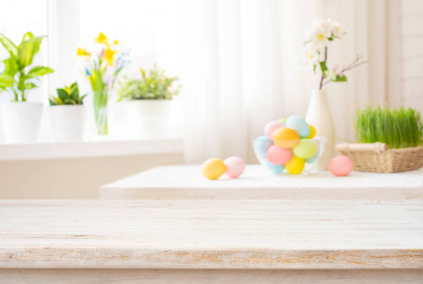 istock Easter table with colorful eggs and spring flowers on blurred kitchen window background 1979448132