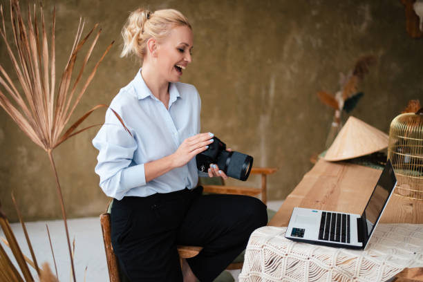 istock Woman holding digital camera and looking at laptop screen 1979472390