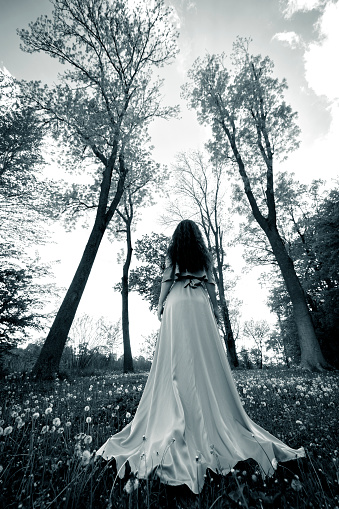 Black and white image with a young woman in dress admiring the nature surroundings.