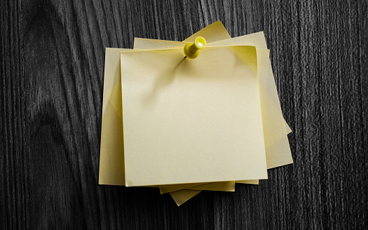 Blank yellow adhesive note on wooden board