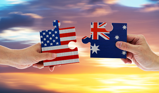Hand holding USA and Australia flags on puzzle pieces joining together