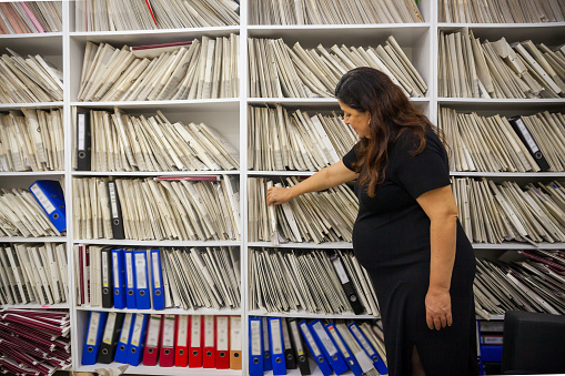 Pregnant women looking at file shelf