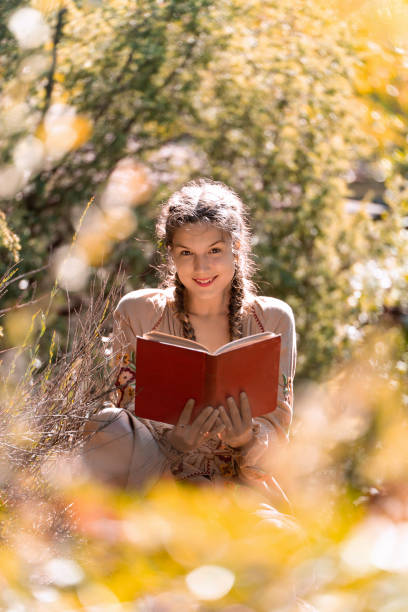 istock Young woman smiling while reading a book in nature. 1979524024