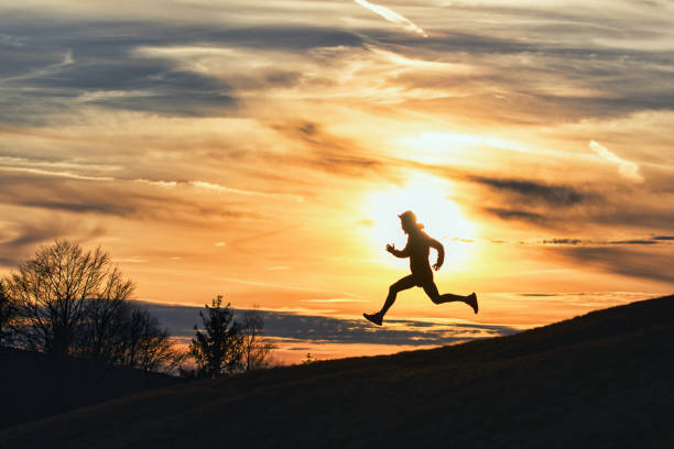 istock Sporty man runs down hill in silhouette 1979530847